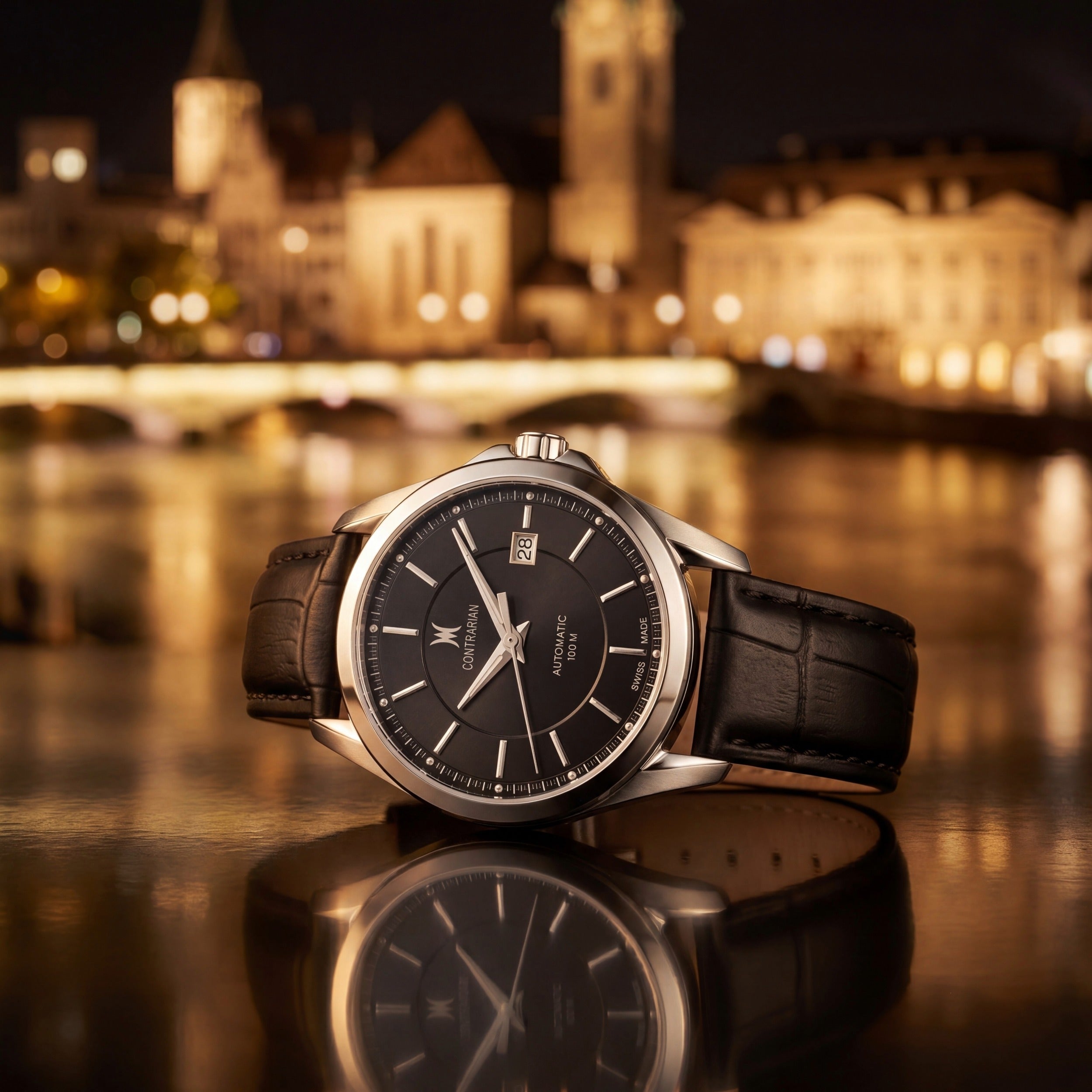 Luxury watch with black leather strap on a reflective surface with a blurred cityscape in the background