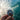 Hand holding a wristwatch with a wave in the background