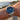 Person wearing a silver watch with a black dial by the ocean