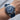 Blue watch with silver case on a wrist against a neutral background