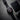 Black wristwatch with a red face on a dark textured surface, next to a black wallet.