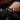 Close-up of a person wearing a black wristwatch with a red face.