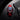 Watch with red strap and black case next to a black wallet with a logo on a reflective surface