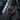 Watch with a black face and red and blue accents on a dark surface with a passport and ticket.