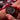 Close-up of a person holding a black wristwatch with a blurred racing car in the background