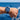 Hand wearing a blue watch with a blue ocean background