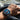 Hand wearing a blue watch with a road in the background