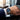 Hand wearing a blue watch with a blurred office background