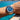 Silver watch with blue face on a wrist by a body of water