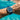 Blue wristwatch with a blue strap worn by a person underwater.
