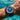 Blue wristwatch with white face on a person's wrist by a pool