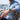 Man wearing a blue shirt and watch sitting by a marina with boats in the background