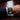 Close-up of a wrist wearing a black watch with a silver bracelet on a wooden surface.