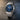 Silver watch with a blue dial on a dark textured background