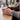 Person holding a cup of coffee with a watch on a wooden table in a cafe.