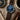Watch with blue dial and brown leather strap on a textured surface with a compass, coffee cup, and pen.